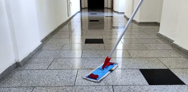 Mopping the tiled hallway of an apartment building with a flat mop